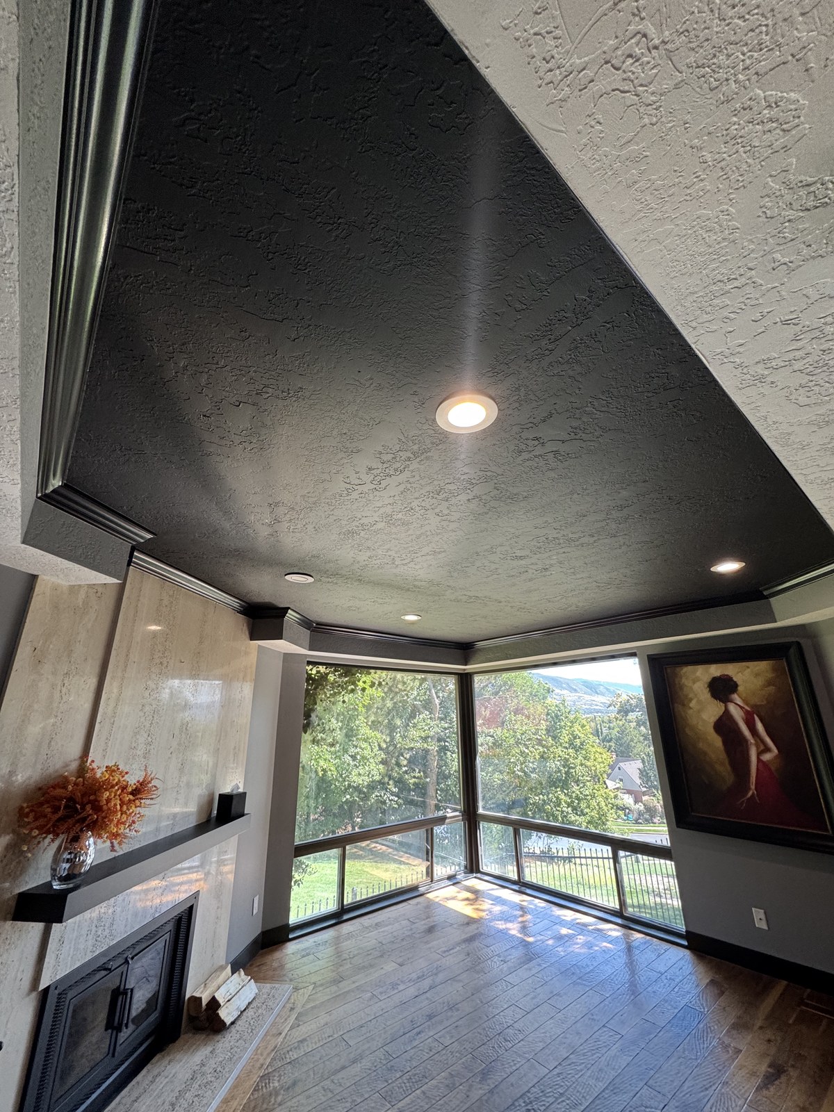 Finished great room with a black painted ceiling, dark crown molding, gray walls, and large windows